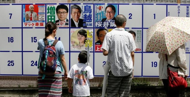Una familia observa los posters de los candidatos a gobernador de Tokio antes de ir a votar. EFE