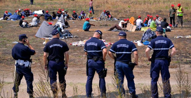 Policías serbios vigilan a un grupo de refugiados que permanecen en huelga de hambre en la frontera serbo-húngara cerca de Horgos. EFE