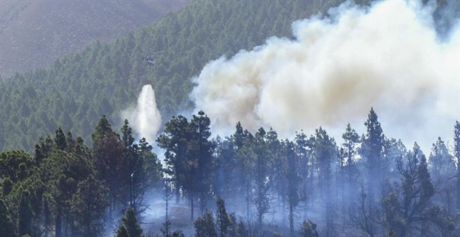 Un helicóptero descarga agua sobre el fuego que comenzó ayer en el municipio palmero de El Paso y que continúa activo hoy lo que ha obligado a evacuar a unas 700 personas como medida preventiva y en cuyas labores de extinción se han incorporado de nuevo l