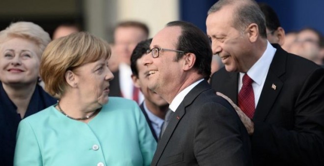 La canciller alemana, Angela Merkel, conversa con el presidente turco, Recep Tayyip Erdogan , en presencia del mandatario francés, François Hollande, durante un cumbre de la OTAN el pasado 8 de julio. - AFP