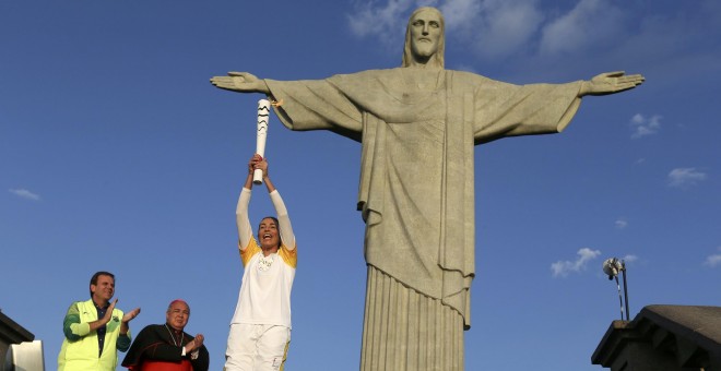 La jugadora de voleibol Isabel Barroso levanta la antorcha ante el Cristo Redentor. /REUTERS