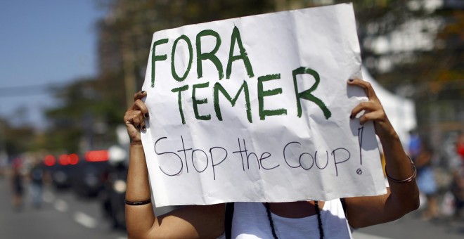 Un manifestante sujeta una pancarta en contra de Temer durante el recorrido de la antorcha olímpica en la playa de Copacabana en Río de Janeiro, Brasil. REUTERS/Benoit Tessier