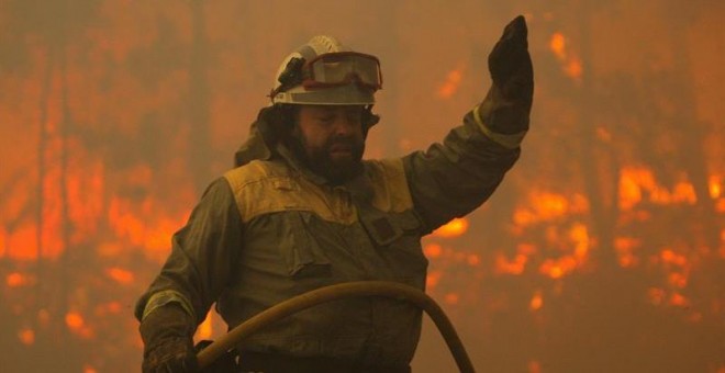 Un brigadista de las cuadrillas contraincendios durante las labores de extinción del incendio forestal registrado en el ayuntamiento de Santiago de Compostela, en la parroquia de Santa Cristina de Fecha.- EFE/Xoán Rey