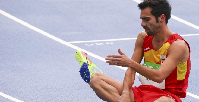 Kevin López se quita la zapatilla tras terminar su serie en los 800 metros, donde ha quedado eliminado. /REUTERS