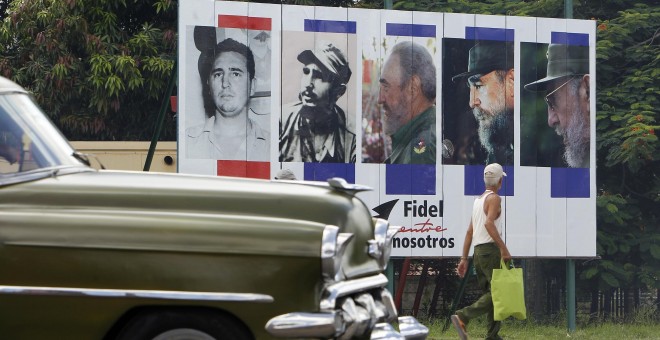 Un vehículo pasa en La Habana junto a un cartel alusivo al cumpleaños 90 del líder de la revolución cubana Fidel Castro. EFE/Ernesto Mastrascusa