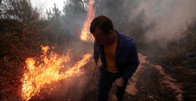 Un hombre apaga las llamas de incendio de Arbo, en Galicia.- REUTERS