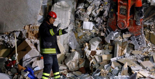 Un bombero trabaja en una de las casas derruidas como consecuencia del seísmo que ha asolado el centro de Italia.- REUTERS
