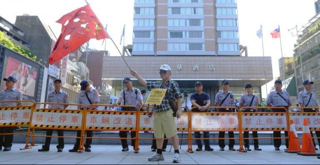 Manifestantes a favor de la independencia de Taiwán ondean una bandera china agujereada en Taipei. - AFP