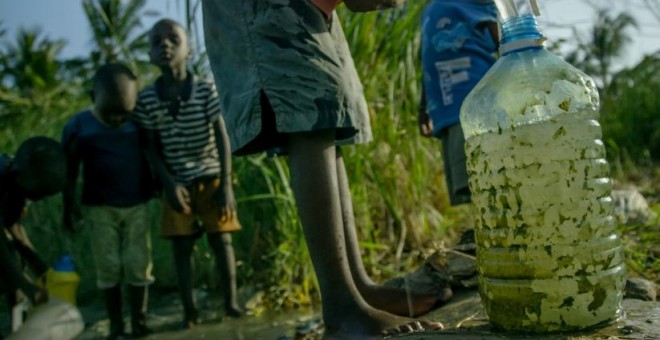 En la imagen, niños de Owino Uhuru, un asentamiento chabolista de Mobasa (Kenia), recogen agua aún contaminada por los vertidos de plomo de una empresa de reciclaje de baterías de coche que fue cerrada después de que murieran y enfermaran numerosos habita