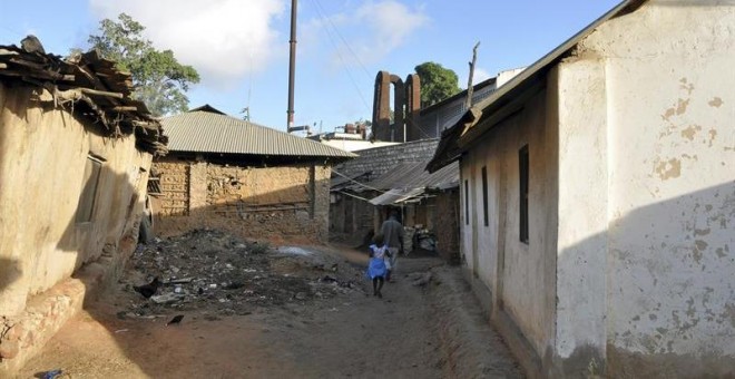 Una niña camina por las calles del poblado chabolista de Owino Uhuru, en Mombasa (Kenia), cuyos habitantes han demandado al Gobierno por permitir la actividad de una fábrica ilegal levantada entre sus viviendas (al fondo) que emitía vertidos de plomo.- EF