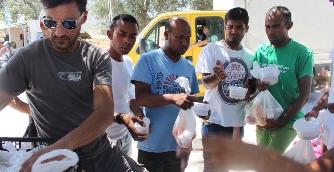 Un vigilante griego reparte comida entre los refugiados de Kara-Tepé, en la isla de Lesbos. - TOMÁS PARRA