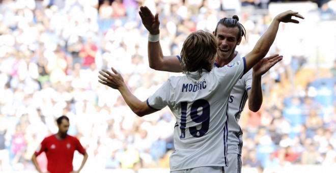 El jugador del Real Madrid, el croata Luka Modric (de espaldas), festeja el gol marcado al Osasuna con su compañero el galés Gareth Bale durante el partido de la tercera jornada de Liga que se ha disputado en el estadio Santiago Bernabéu. EFE/Sergio Barr