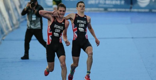 Alistair Brownlee (i) de Gran Bretaña ayuda a su hermano Jonathan Brownlee (d) a terminar la carrera en Cozumel (México). /EFE