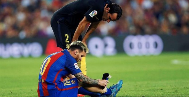 Godín se interesa por Leo Messi tras caer lesionado anoche en el Camp Nou. /EFE