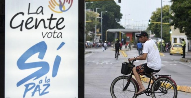 Un hombre monta en bicicleta junto a un cartel promoviendo el voto por el si al acuerdo de paz entre las FARC y el Gobierno de Colombia, en el referendum previsto para el próximo 2 de octubre. AFP / Luis Robayo