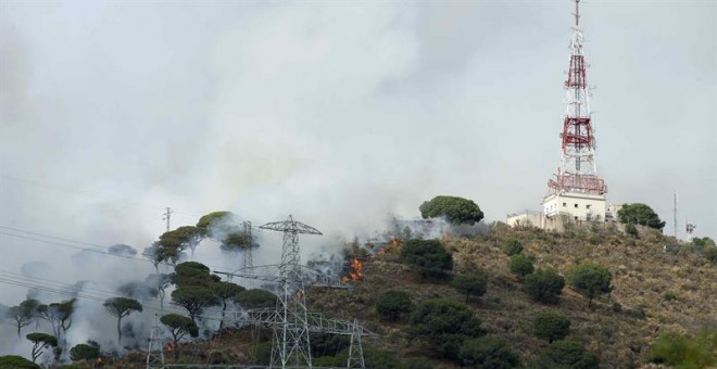 Los Bomberos trabajan en la extinción de un incendio que se ha desatado esta tarde en una zona boscosa del parque natural de Collserola, en el término de Esplugues de Llobregat (Barcelona), y que está originando una espectacular nube de humo visible desde