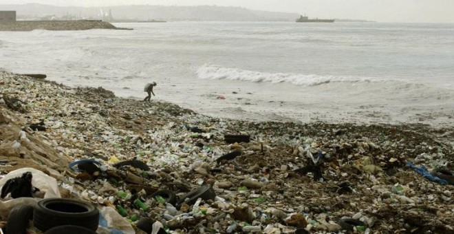 Un hombre recoge basura de entre los montones de plástico de una playa en el sur del Líbano, en la costa Mediterránea. AFP