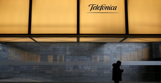 Un hombre debajo del logo de Telefonica, en la sede de la compañía en el distrito de Las Tablas, en el norte de Madrid. REUTERS/Juan Medina