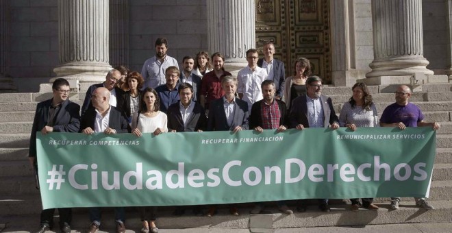 Miembros de Unidos Podemos y representantes de los llamados ayuntamientos 'del cambio' posan  a las puertas del Congreso de los Diputados tras presentar una proposición para derogar la ley de Racionalización y Sostenibilidad de la Administración Local. EF