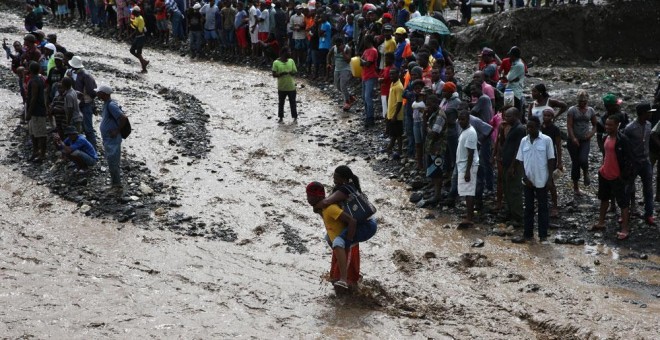 Personas intentan cruzar el río La Digue, debido al derrumbe del único puente que conecta con el sur, tras el paso del huracán Matthew en Haití. EFE