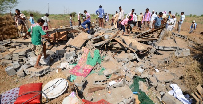 Un grupo de personas permanece de pie junto a una casa destruida por los ataques aéreos de la coalición árabe en Yemen. REUTERS/Abduljabbar Zeyad