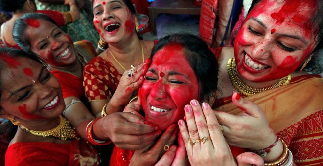 Varias mujeres indias echan sindhur' (polvo bermellón) a una de ellas durante un acto religioso en la ciudad de Chandigarh. - REUTERS