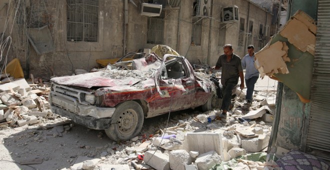 Dos personas pasan por una calle de Alepo destrozada por los últimos bombardeos. - REUTERS