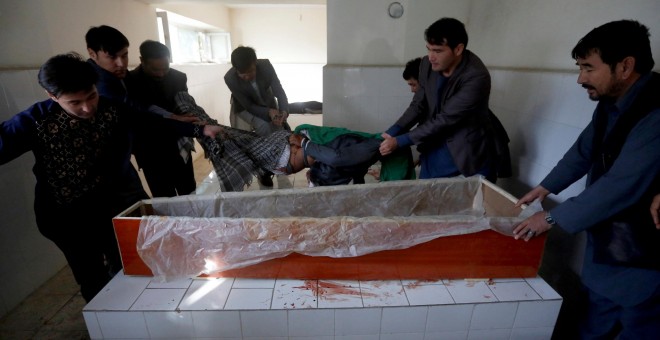 Varias personas levantan el cadáver de un civil muerto en un hospital de Kabul. - REUTERS
