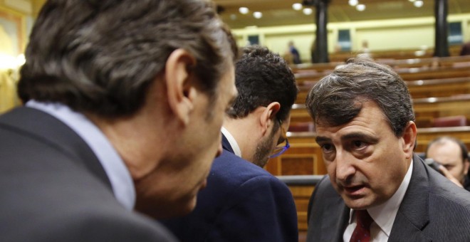 El portavoz parlamentario del PNV, Aitor Esteban, conversa con el portavoz del Grupo Popular, Rafael Hernando, en presencia del diputado socialista Eduardo Madina, durante el pleno del Congreso. EFE/Mariscal