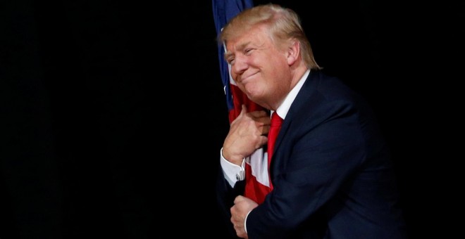 El candidato republicano a la presidencia de Estados Unidos, Donald Trump, abraza una bandera nacional durante un mítin en Tampa, Florida. REUTERS/Jonathan Ernst