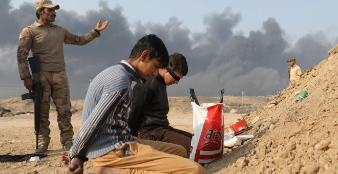 Un soldado iraquí junto a dos detenidos acusados de pertenecer al Estado Islámico, en un puesto de control en la localidad de Qayyara, al sur de Mosul. REUTERS/Goran Tomasevic