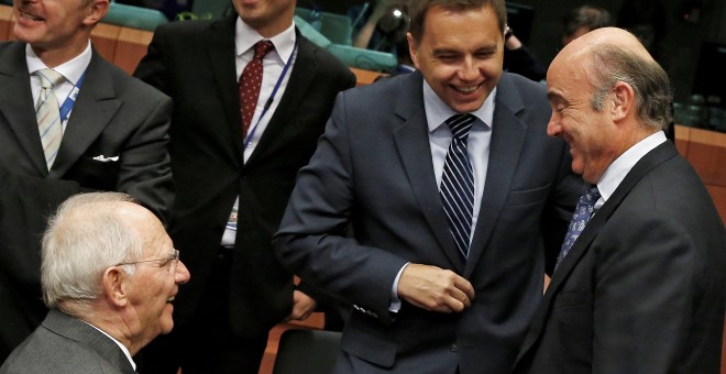 El ministro de Economía, Luis de Guindos, conversa con el titular alemán de Finanzas, Wolfgang Schaeuble, y el ministro eslovaco Peter Kazimir, antes de la reunión del Eurogrupo en Bruselas, el primer tras el nombramiento del nuego Gobierno de Mariano Raj