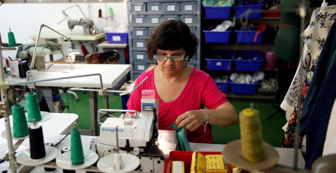 Una mujer trabajando en un taller textil./ REUTERS