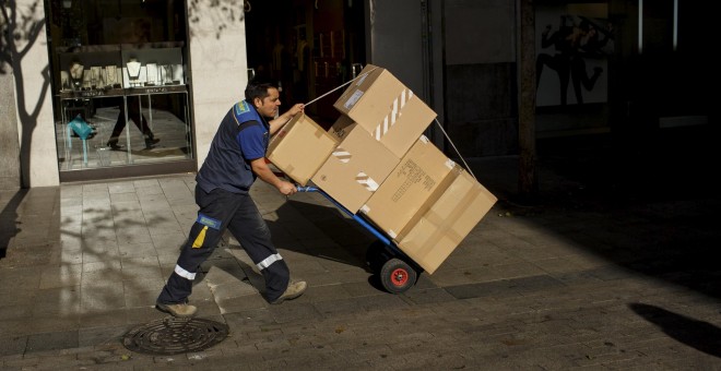 Un trabajador transporta en una carretillas varios paquetes por el centro de Madrid. REUTERS