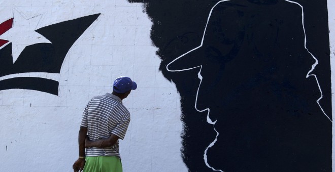 Un hombre mira un mural de Fidel Castro en las afueras de Santiago de Cuba. REUTERS