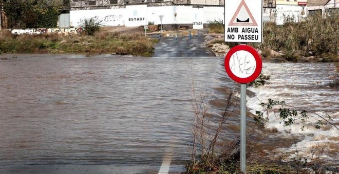 La Policía local de Sagunto ha cortado esta carretera que cruza el cauce habitualmente seco del barranco del río Palancia en Sagunto tras su crecida por las lluvias. La Agencia Estatal de Meteorología (Aemet) mantiene para hoy la alerta naranja por tempor