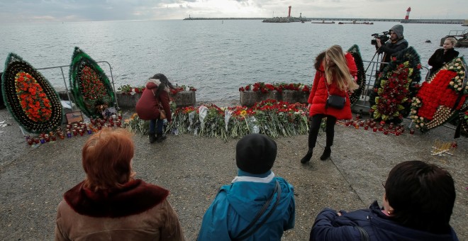 Varias personas depositan flores en un embarcadero en Sochi en memoria de los fallecidos en el avión siniestrado en el Mar Negro. /REUTERS