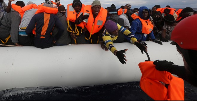Un voluntario de Proactiva Open Arms acerca un achaleco salvavidas a los inmigrantes que tratan de rescatar en el Mediterráneo.-REUTERS/Yannis Behrakis