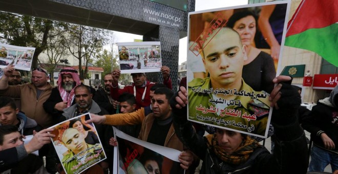 Una multitud sostiene pancartas con la fotografía del soldado israelí Elor Azaría, que mató de un tiro en la cabeza a un joven palestino, durante una protesta contra él en Hebrón. EFE