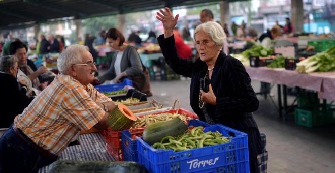 Una mujer hace la compra en un puesto de un mercado de Bilbao. REUTERS