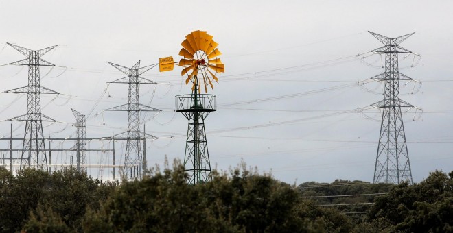 Un molino de viento cerca de unas torres eléctricas de alta tensión en la localidad madrileña de Galapagar. REUTERS