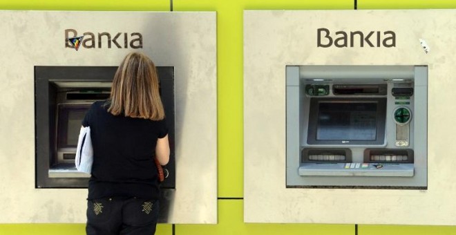 Una mujer opera en un cajero automático en una sucursal de Bankia en Madrid. AFP