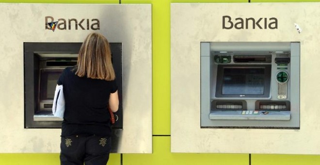 Una mujer opera en un cajero automático en una sucursal de Bankia en Madrid. AFP