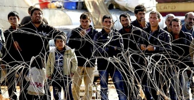 Refugiados sirios esperan para cruzar la frontera y pasar a Turquía cerca de Kobane (Siria). EFE/Archivo