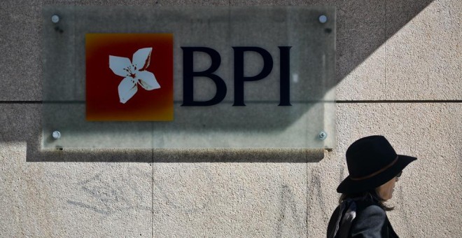 Una mujer pasa junto a una oficina del banco BPI en Lisboa.  AFP / Patricia de Melo Moreira