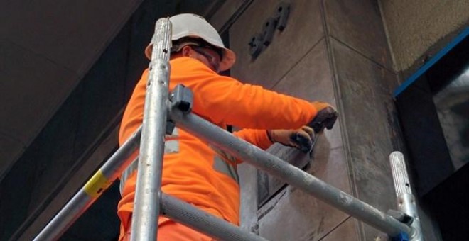 Un operario retira una placa franquista en Barcelona.