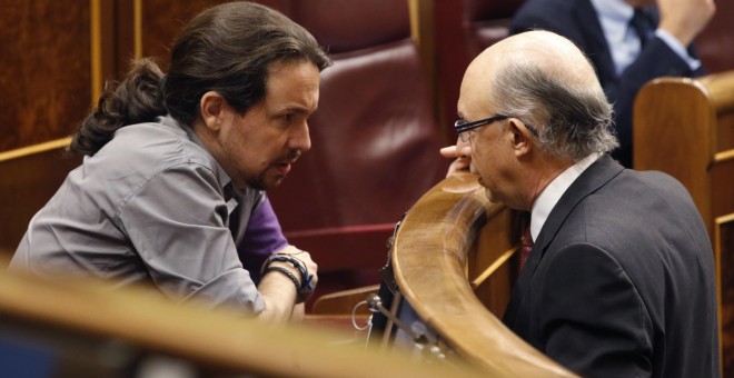 El ministro de Hacienda, Cristóbal Montoro, conversa con el líder de Podemos, Pablo Iglesias, durante un Pleno del  Congreso de los Diputados. EFE/Javier Lizón