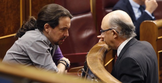 El ministro de Hacienda, Cristóbal Montoro, conversa con el líder de Podemos, Pablo Iglesias, durante un Pleno del  Congreso de los Diputados. EFE/Javier Lizón