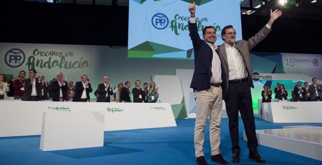 El presidente del Gobierno, Mariano Rajoy (d), y el líder del PP andaluz, Juanma Moreno (i), saludan tras finalizar la intervención del jefe del Ejecutivo, durante la clausura del 15 Congreso Autonómico del Partido Popular que se ha celebrado este fin de