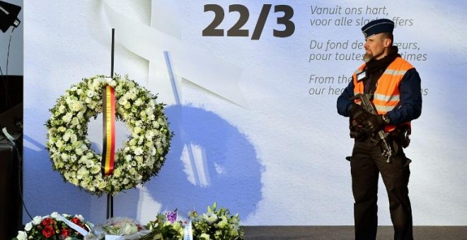 Un policía monta guardia junto a un mural en memoria de las víctimas de los atentados del 22 de marzo de 2016. - AFP